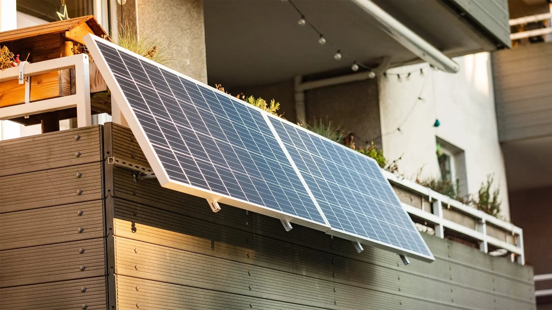Zwei Solarmodule an der Brüstung eines Balkons, im Hintergrund eine Lichterkette