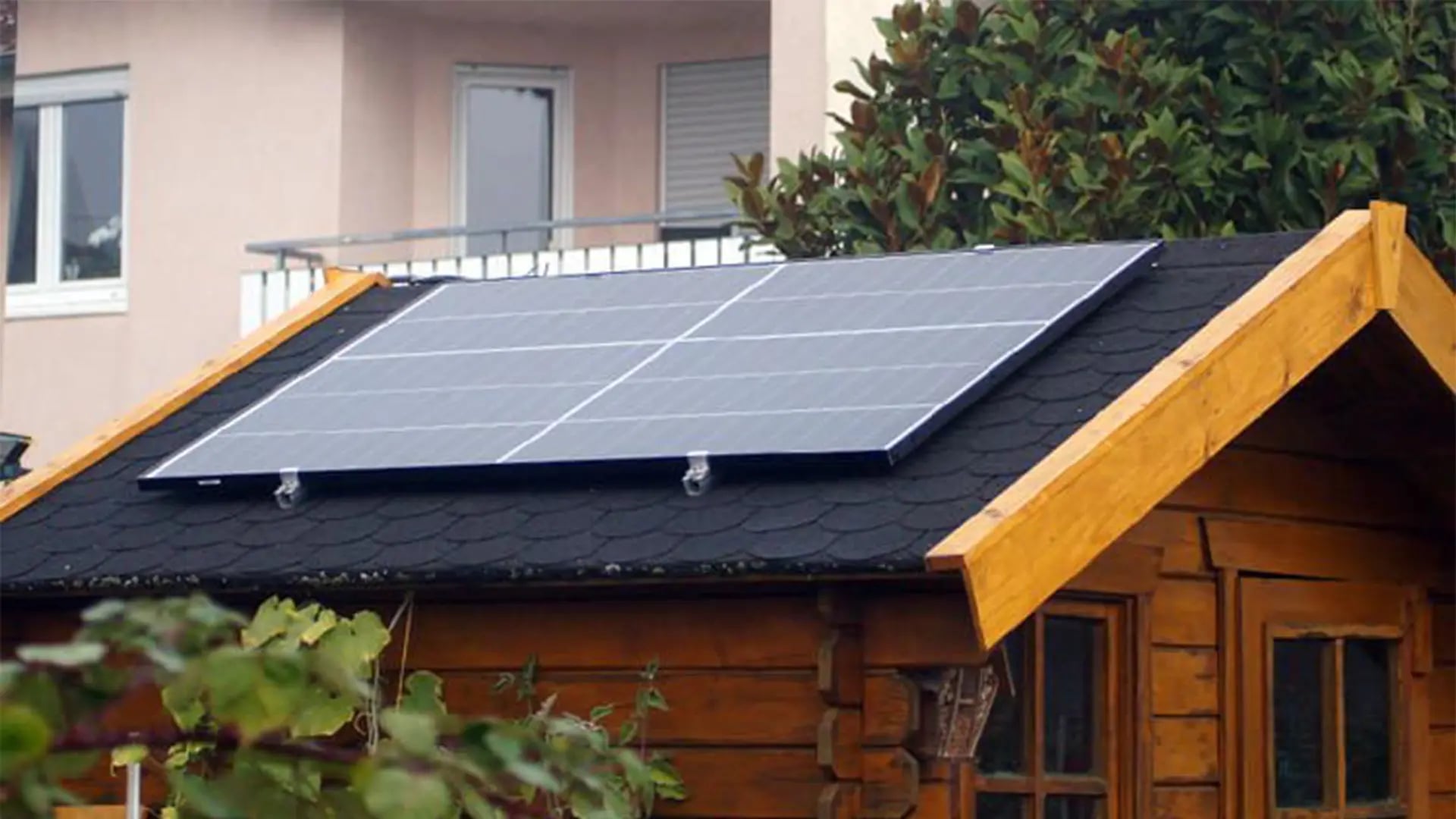 Solarmodul auf dem schwarzen Schindeldach eines hölzernen Gartenhauses