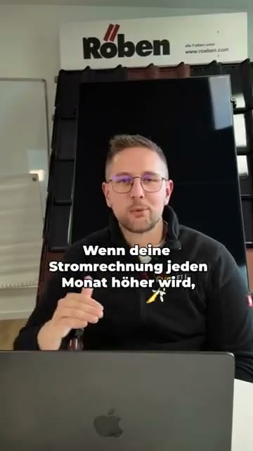 Standbild des Videos: ein Mitarbeiter mit Brille und schwarzer Firmenjacke sitzt lächelnd hinter einem aufgeklappten Laptop, hinter ihm ein schwarzes Solarmodul und eine Musterwand mit Dachziegeln; eingeblendet der gelbe Satz „Mensch, war das einfach. Alles innerhalb von einem Tag fertiggestellt.“