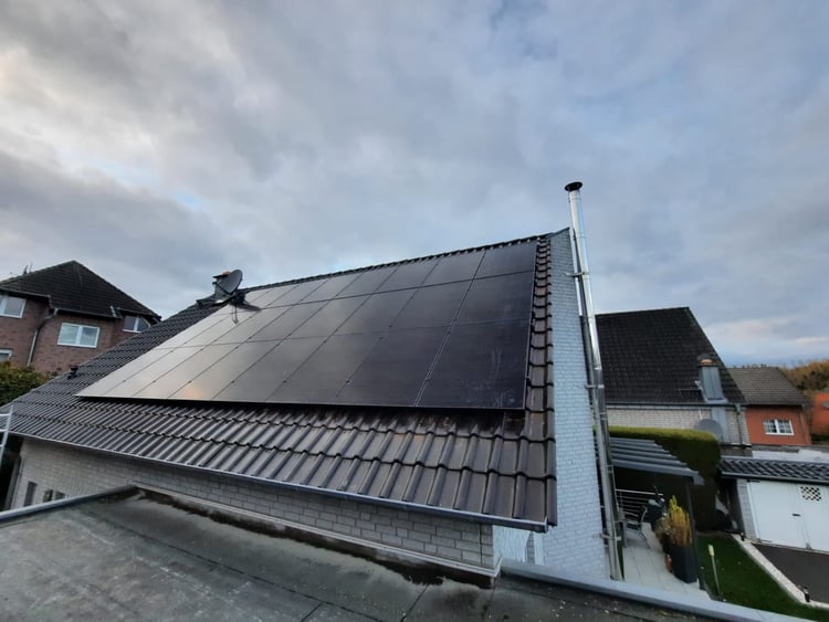 Schwarze Solarmodule auf der dunklen Ziegeldachfläche eines Hauses in Jülich Koslar unter bewölktem Himmel