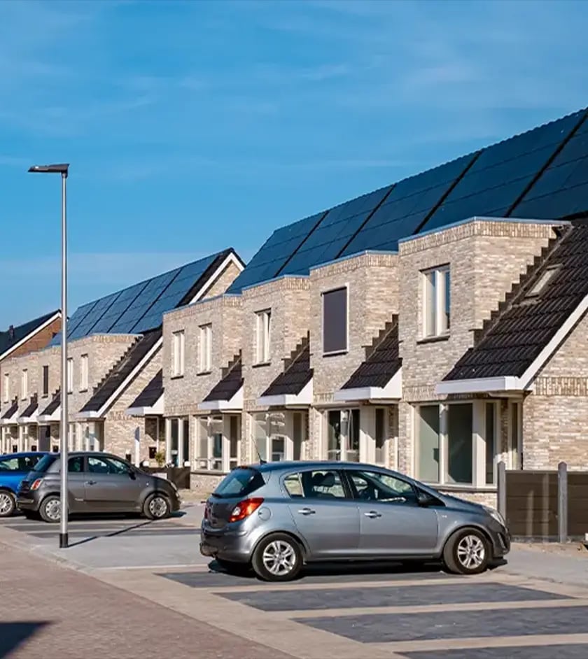 Reihenhauszeile, deren Dächer durchgehend mit Photovoltaikmodulen belegt sind, davor eine Wohnstraße