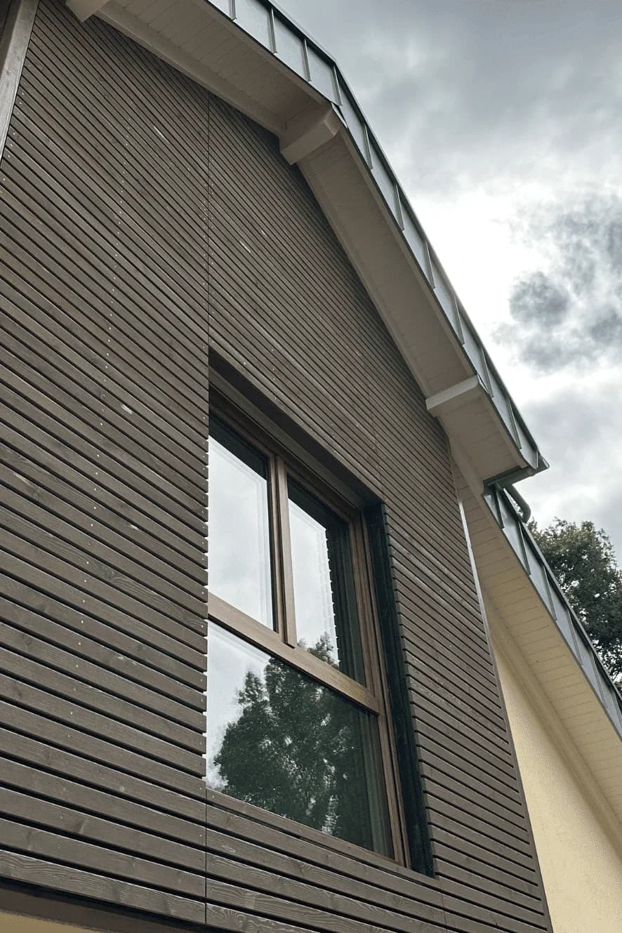 Dunkle Holzfassade mit Fenster unter einem Satteldach