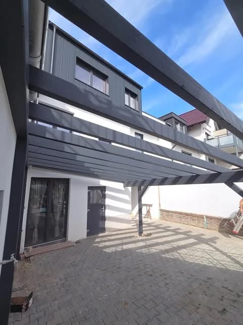 Dunkle Holzpergola an einem Wohnhaus
